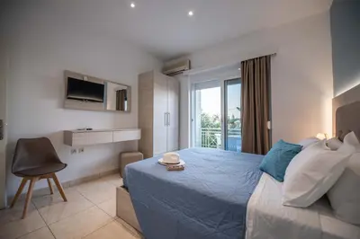 a bedroom with a large bed and a balcony at Stegna Bay Apartment in Archangelos