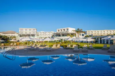 a swimming pool with chairs and umbrellas in a resort at Asterias Beach Resort in Afantou