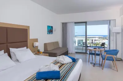 a hotel room with a bed and a table and chairs at Asterias Beach Resort in Afantou