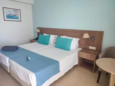 a bedroom with two beds with blue pillows and a table at Asterias Beach Resort in Afantou