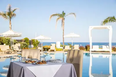 a table with a plate of food next to a swimming pool at Asterias Beach Resort in Afantou