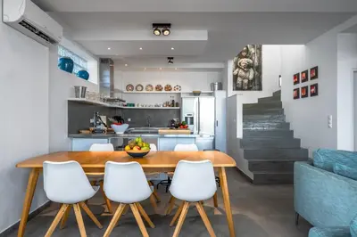 a kitchen and dining room with a wooden table and white chairs at Kokinogremos Villa in Kalithies