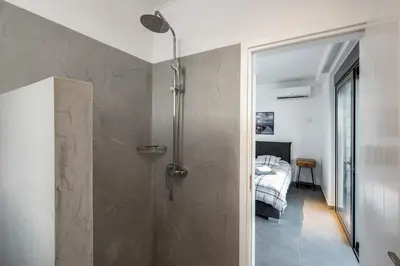 a bathroom with a shower and a bedroom at Kokinogremos Villa in Kalithies