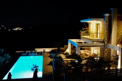 a person standing in front of a swimming pool at night at Kokinogremos Villa in Kalithies