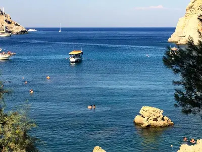 a boat in a body of water with people swimming at Kokinogremos Villa in Kalithies