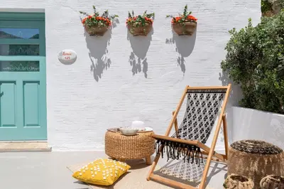 a porch with a chair and flowers on a wall at Kaminos Boutique Hotel in Symi