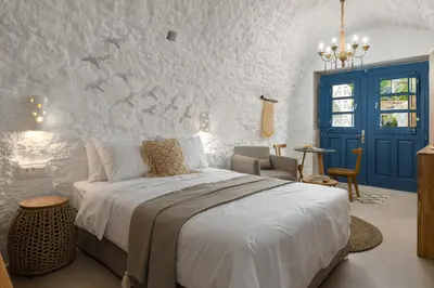 a bedroom with a large bed and a blue door at Kaminos Boutique Hotel in Symi