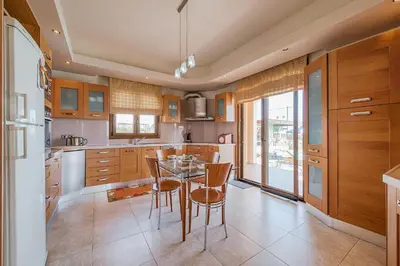 a kitchen with wooden cabinets and a table and chairs at Villa Rose in Kolimbia