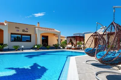 a pool with swings in front of a hotel at Villa Rose in Kolimbia