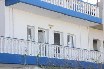 a white and blue building with a balcony at Nikos Studios Meltemi Family Suite Penthouse in Archangelos