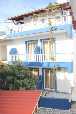 a blue and white building with a red roof at Nikos Studios Meltemi Family Suite Penthouse in Archangelos