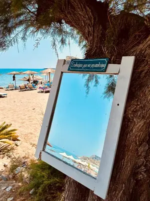 a sign hanging from a tree on the beach at Apágkio Filoxenia in Archangelos