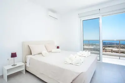 a white bedroom with a white bed and a large window at Sea view villa with private pool Horizontes in Kalithies