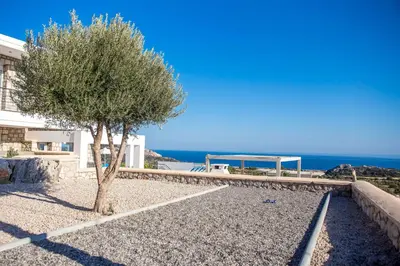 a tree and a gazebo in front of a building at Sea view villa with private pool Horizontes in Kalithies