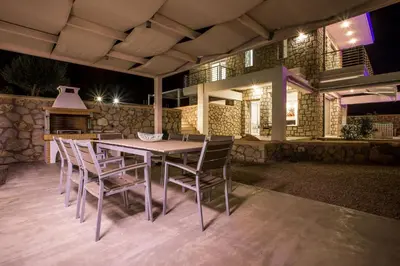 a table and chairs on a patio at night at Sea view villa with private pool Horizontes in Kalithies