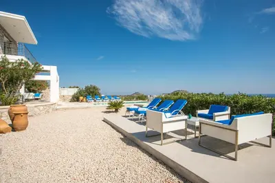a row of blue and white chairs on a patio at Sea view villa with private pool Horizontes in Kalithies