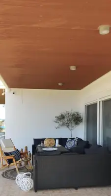 a black couch in a living room with a wooden ceiling at Kamiros Apartment in Kalavárda