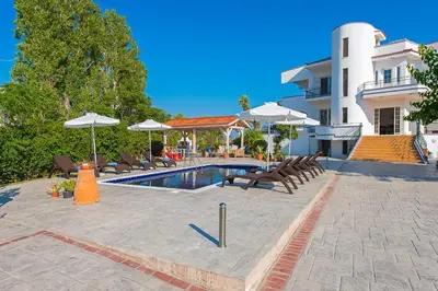 a swimming pool with chairs and umbrellas next to a building at Villa Giovanni in Faliraki