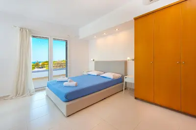 a bedroom with a bed and a large window at Villa Giovanni in Faliraki