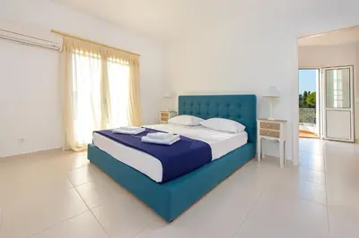 a white and blue bedroom with a blue bed at Villa Giovanni in Faliraki