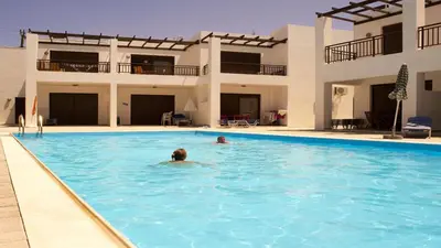 a man swimming in a swimming pool in front of a house at Harmonia at Gennadi Court in Gennadi