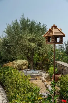 a bird house and a pond in a garden at Harmonia at Gennadi Court in Gennadi