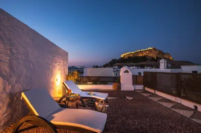 a couple of chairs sitting on a balcony at night at Antique Villa in Líndos
