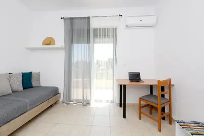 a living room with a couch and a table and a desk at Athina's Apartment in Olive Grove in Faliraki