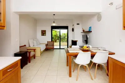 a kitchen and living room with a table and chairs at Athina's Apartment in Olive Grove in Faliraki