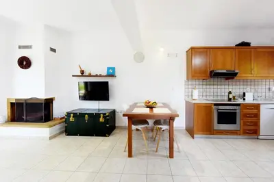 a kitchen with wooden cabinets and a wooden table at Athina's Apartment in Olive Grove in Faliraki