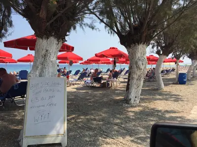 a sign on the beach with people sitting under umbrellas at Alkyonides Boutique Hotel in Kremasti