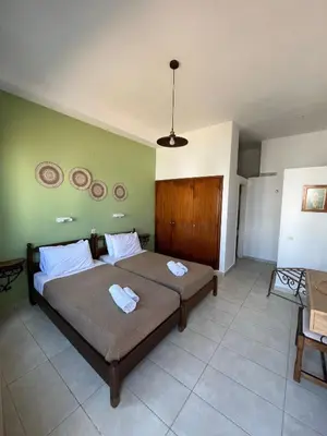 a bedroom with two beds and a green wall at Aphrodite White Studios Lindos in Líndos
