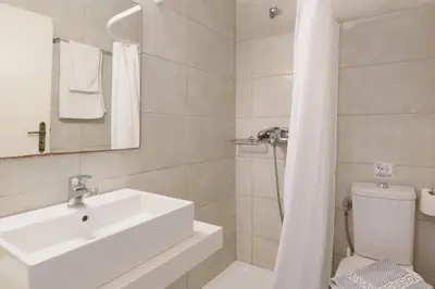 a white bathroom with a sink and a toilet at Aphrodite White Studios Lindos in Líndos