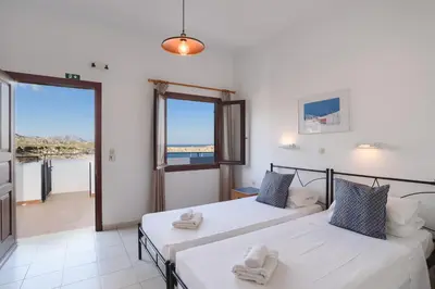two beds in a room with a view of the ocean at Aphrodite White Studios Lindos in Líndos