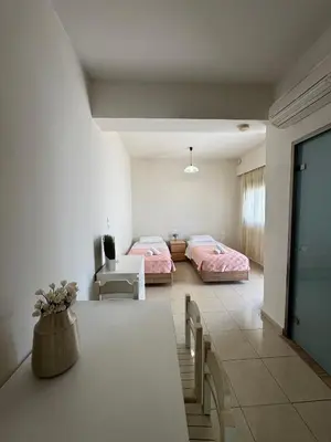 a bedroom with two beds and a table in a room at Steve's Beach in Faliraki