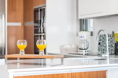 two glasses of orange juice on a cutting board on a kitchen counter at Francis & Gregorys Luxury Villas in Afantou