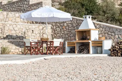 a table and chairs with an umbrella and a grill at Francis & Gregorys Luxury Villas in Afantou