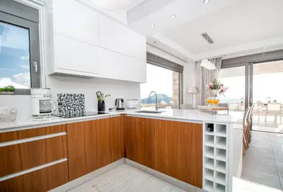 a kitchen with white cabinets and a large window at Francis & Gregorys Luxury Villas in Afantou