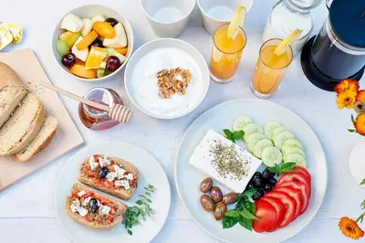 a white table with plates of food and drinks at Helios Garden Boutique Apartments in Rhodes Town