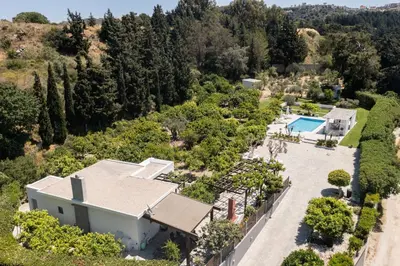 an aerial view of a house with a pool and trees at Antigone Estate in Koskinou