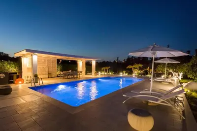a swimming pool with an umbrella and a patio at Antigone Estate in Koskinou