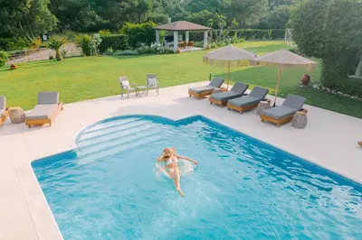 a woman jumping into a swimming pool at Bello Blu Luxury Villa in Asgourou