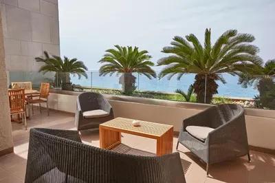 a patio with chairs and a table and a view of the ocean at Sheraton Rhodes Resort in Ixia