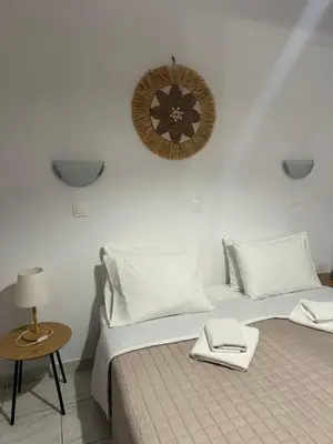 a bedroom with two beds and a clock on the wall at Fedra Apartments Lindos in Líndos