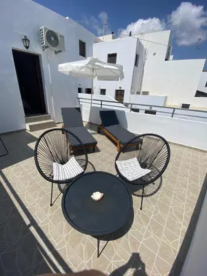 a patio with three chairs and a table and an umbrella at Fedra Apartments Lindos in Líndos