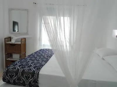 a bedroom with a white bed with a curtain at Tilos Island house in Megálon Choríon