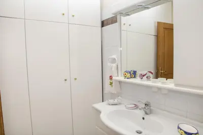 a white bathroom with a sink and a mirror at Aggeli Village House in Asklipiḯon