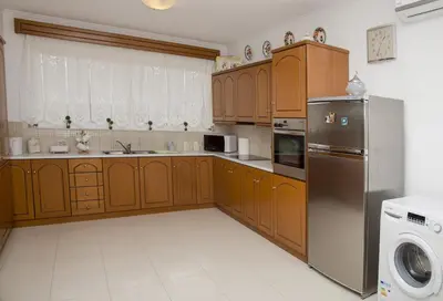 a kitchen with wooden cabinets and a stainless steel refrigerator at Aggeli Village House in Asklipiḯon