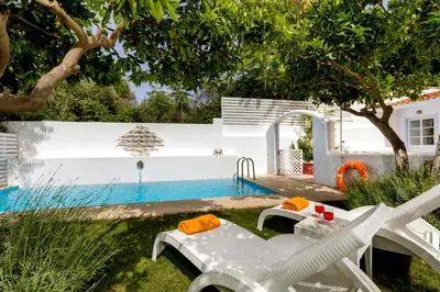 a backyard with a pool and chairs and a swimming pool at Amelie Villa in Ixia