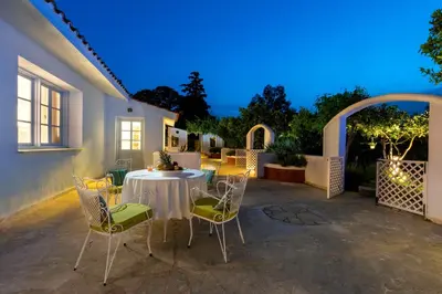 a patio with a table and chairs at night at Amelie Villa in Ixia